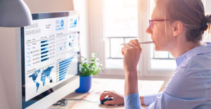 Businesswoman looking at business analytics (BA) or intelligence (BI) dashboard on the computer screen with sales data statistical report and key performance indicators (KPI)