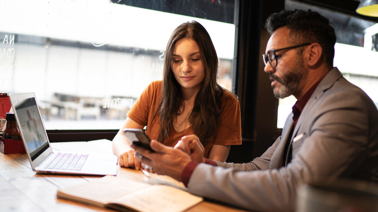 People at a table with papers looking at a cell phone screen