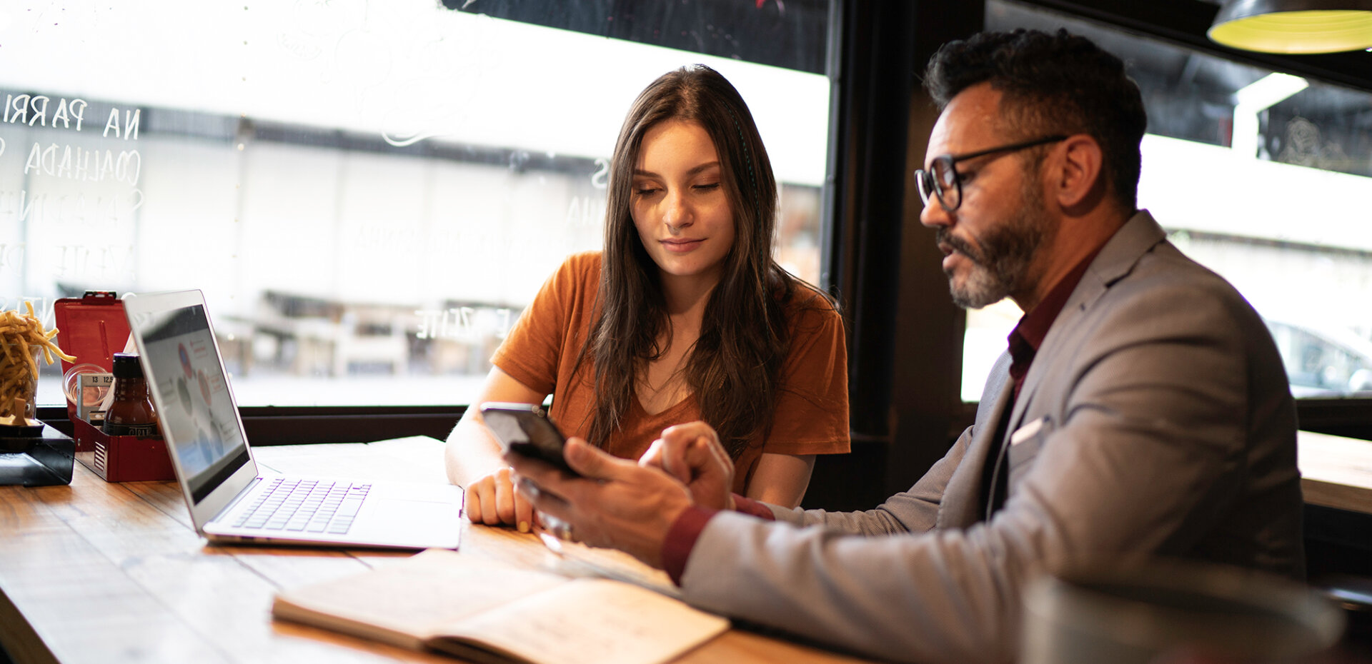 People at a table with papers looking at a cell phone screen