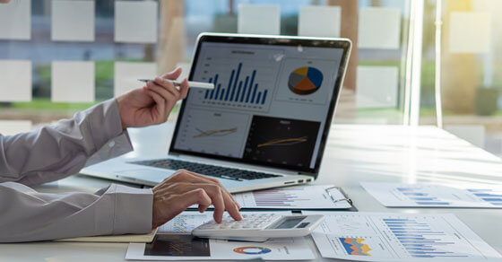 laptop on a table with charts on the screen and on the table