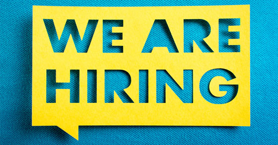 yellow stencil with the words "we are hiring" cut out and placed on top of a blue print