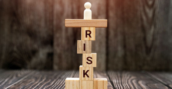 "risk" spelled out on jenga blocks stacked on top of each other on a table