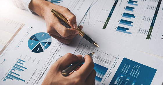 people at a desk looking at papers that have graphs on them.