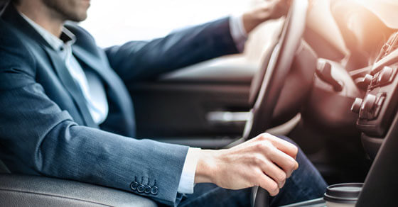 image of a person in a business suite driving a car.