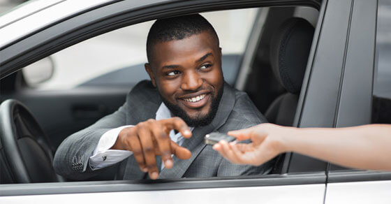 individual handed car keys while sitting in a car.