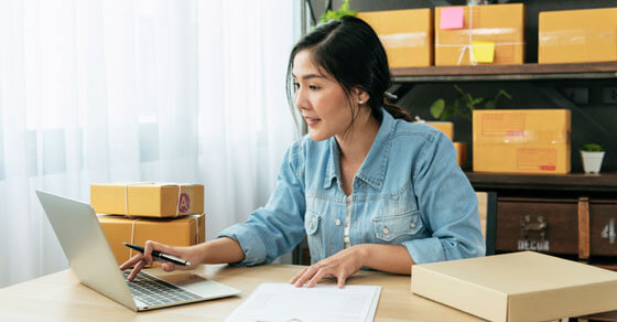 Individual on a laptop at a desk looking at papers