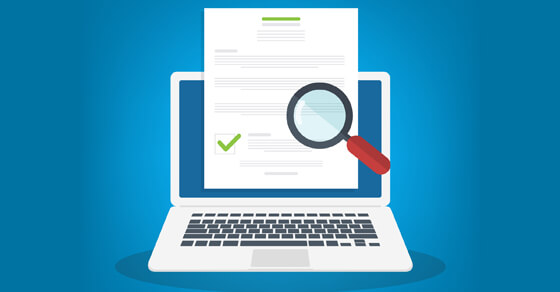 laptop with magnifying glass on paper