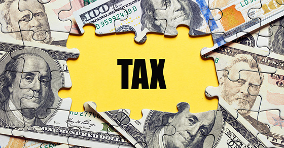 puzzle of money with pieces in the center removed and the word "tax" is uncovered