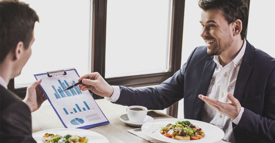 two individuals looking over spreadsheets at a restaurant.