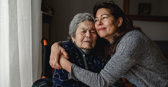 Two woman, possibly an elderly mother and her daughter, embracing.