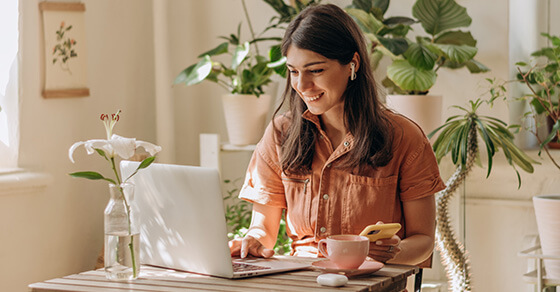 Image of smiling individual on a laptop looking at the screen.