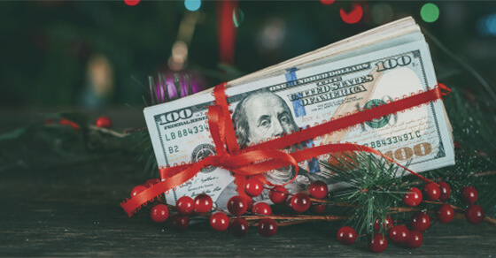 bundle of bills wrapped up in a red bow and placed in a christmas tree.