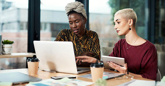 Cropped shot of two attractive young business colleagues working on a laptop and a tablet in the office