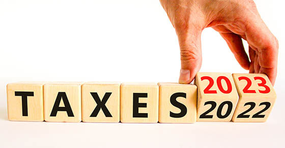 2023 taxes new year symbol. Businessman turns a wooden cube and changes words Taxes 2022 to Taxes 2023. Beautiful white table white background, copy space. Business 2023 taxes new year concept.