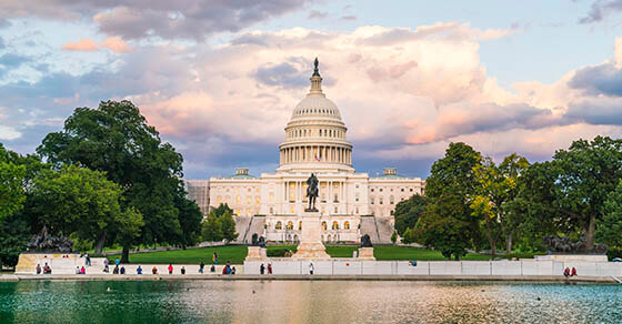 The United States Capitol building at sunset wirh reflection in water.