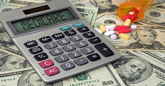calculator and a spilled pill bottle on top of cash.
