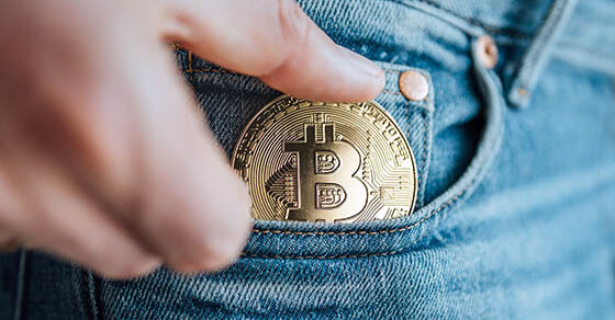 Close up footage of man's fingers putting the Bitcoin coin in the blue jeans small pocket. Savings, digital currency, cryptocurrency, investing, and smart outgoings managing concept.