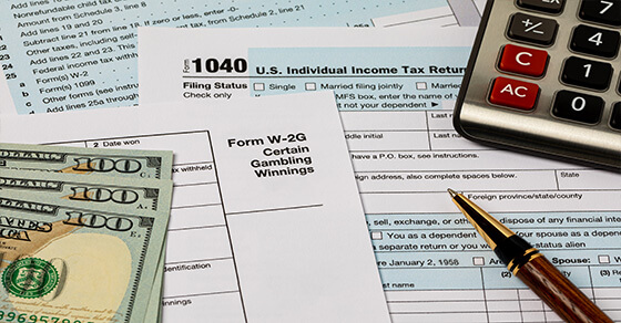 tax forms with cash and a calculator on a table. 