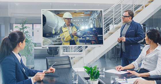 In the Conference Room Group of Directors, Investors and Businessmen Making Video Conference Call To Talk with Professional Female Engineer with Tablet Computer, working in Industrial Factory