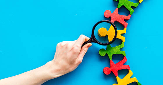 Wooden figures of people under black magnifying glass on blue desk. Recruitment, hiring, leadership concept.