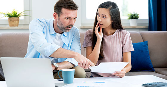 Image of a couple sitting at a table filled with paperwork.