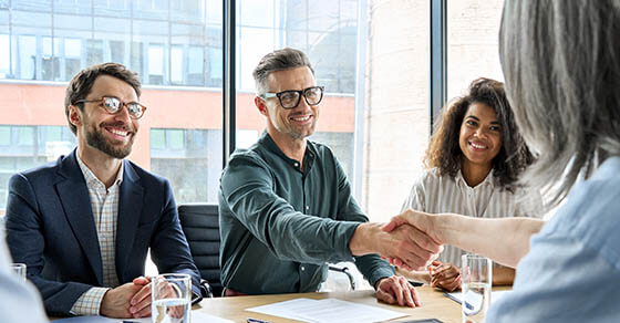 Happy businessman and businesswoman shaking hands at group board meeting. Professional business executive leaders making handshake agreement successful company trade partnership handshake concept.