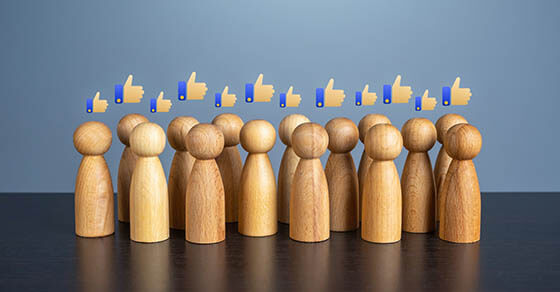 images of wooden people on a table with thumbs up emojies above their heads.