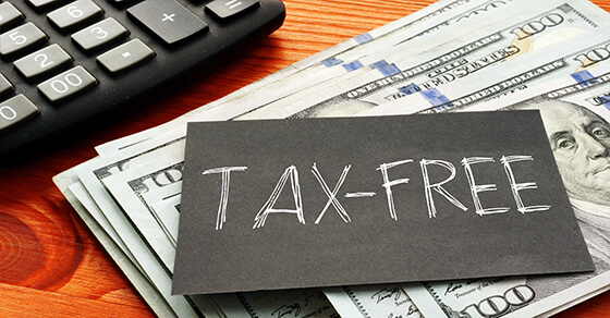 cash and a calculator on a table with the sign "Tax-Free" on top. 