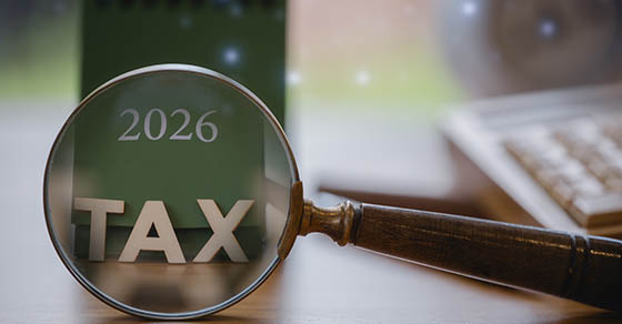 2026 tax concept with magnifying glass highlighting TAX on a green calendar, symbolizing financial review, tax analysis, accounting, deadlines, and fiscal planning