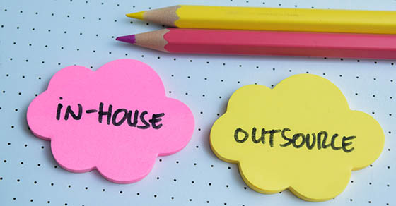 Concept of In-House or Outsource write on sticky notes isolated on Wooden Table.